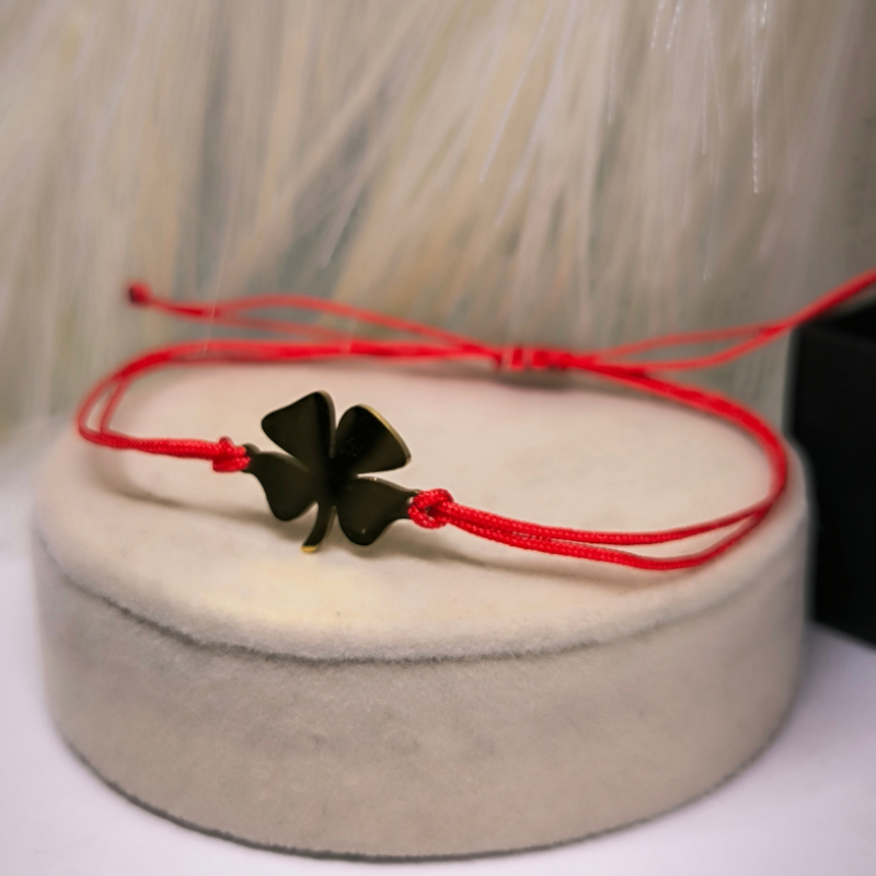 Sarkanā diega rokassprādze ar zelta krāsas četrplaukstu āboliņu