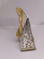 Balta dāvanu kastīte ar zelta ornamentiem un lentīti