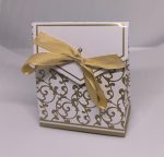 Balta dāvanu kastīte ar zelta ornamentiem un lentīti