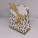 Balta dāvanu kastīte ar zelta ornamentiem un lentīti