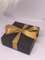 Melna dāvanu kastīte ar zelta lentīti