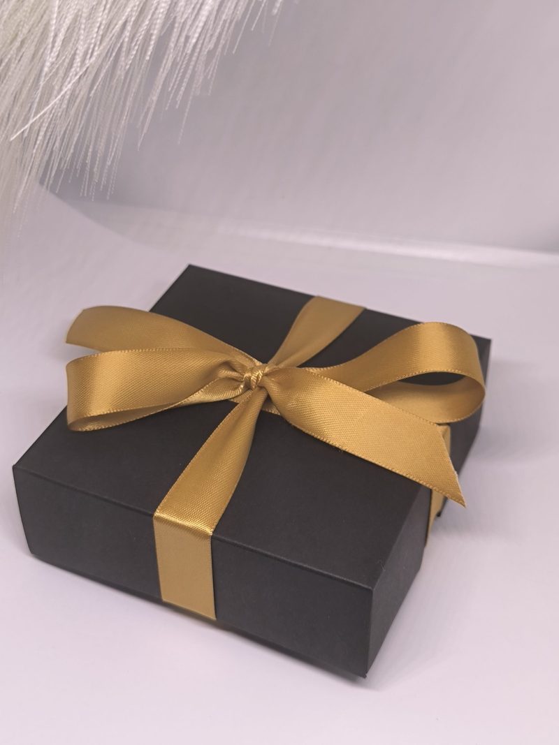 Melna dāvanu kastīte ar zelta lentīti